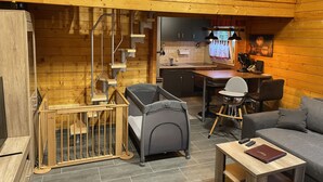 L’intérieur chaleureux d’un chalet avec un escalier en bois, un coin repas et un salon comprenant un canapé et une table.