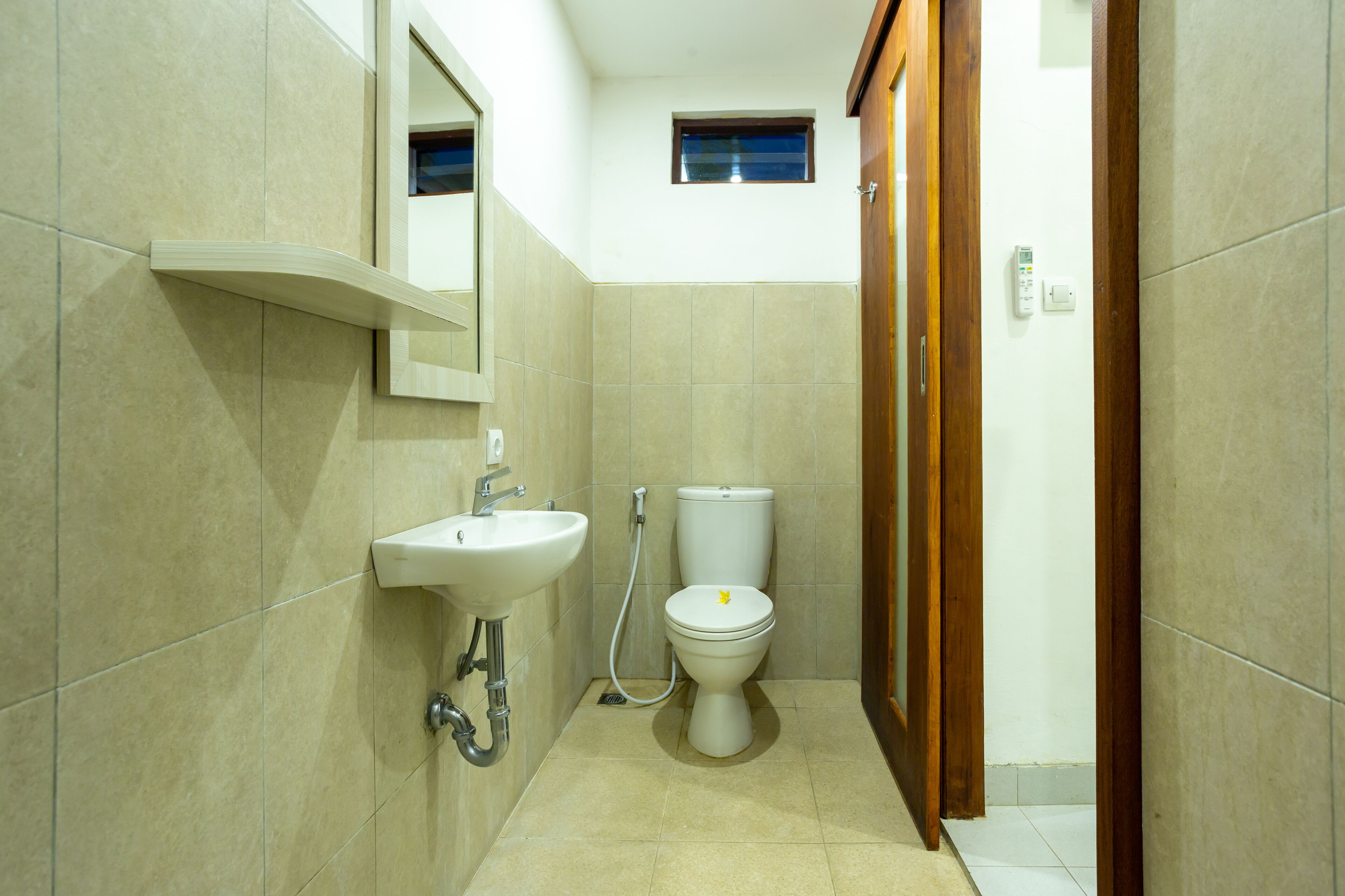 Un baño con lavamanos, inodoro y un ventanal pequeño.