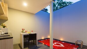 A modern bathroom with a small sink, a chair, and a heated floor with red and white flower petals. - Radea Villa (Kerobokan)