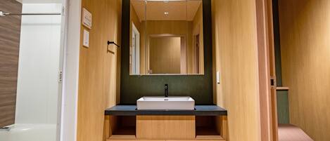 Un baño moderno con un mueble de tocador de madera, un lavabo y un espejo.