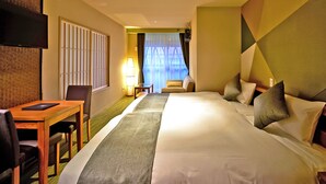 Habitación de hotel con una cama grande, un escritorio, una silla, un televisor y vistas al exterior a través de una ventana.