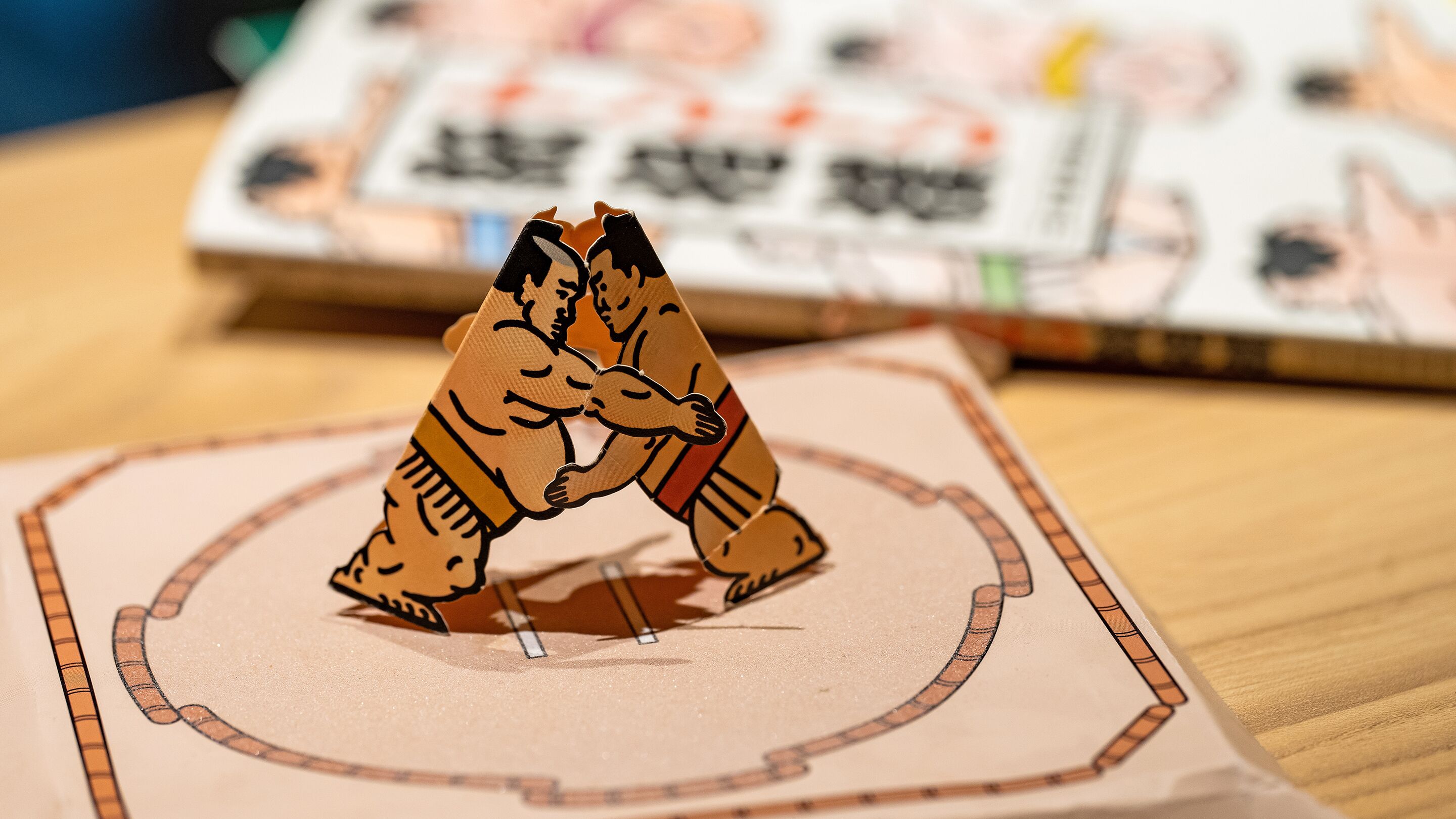 A card game with two figures in a fighting stance on a table.