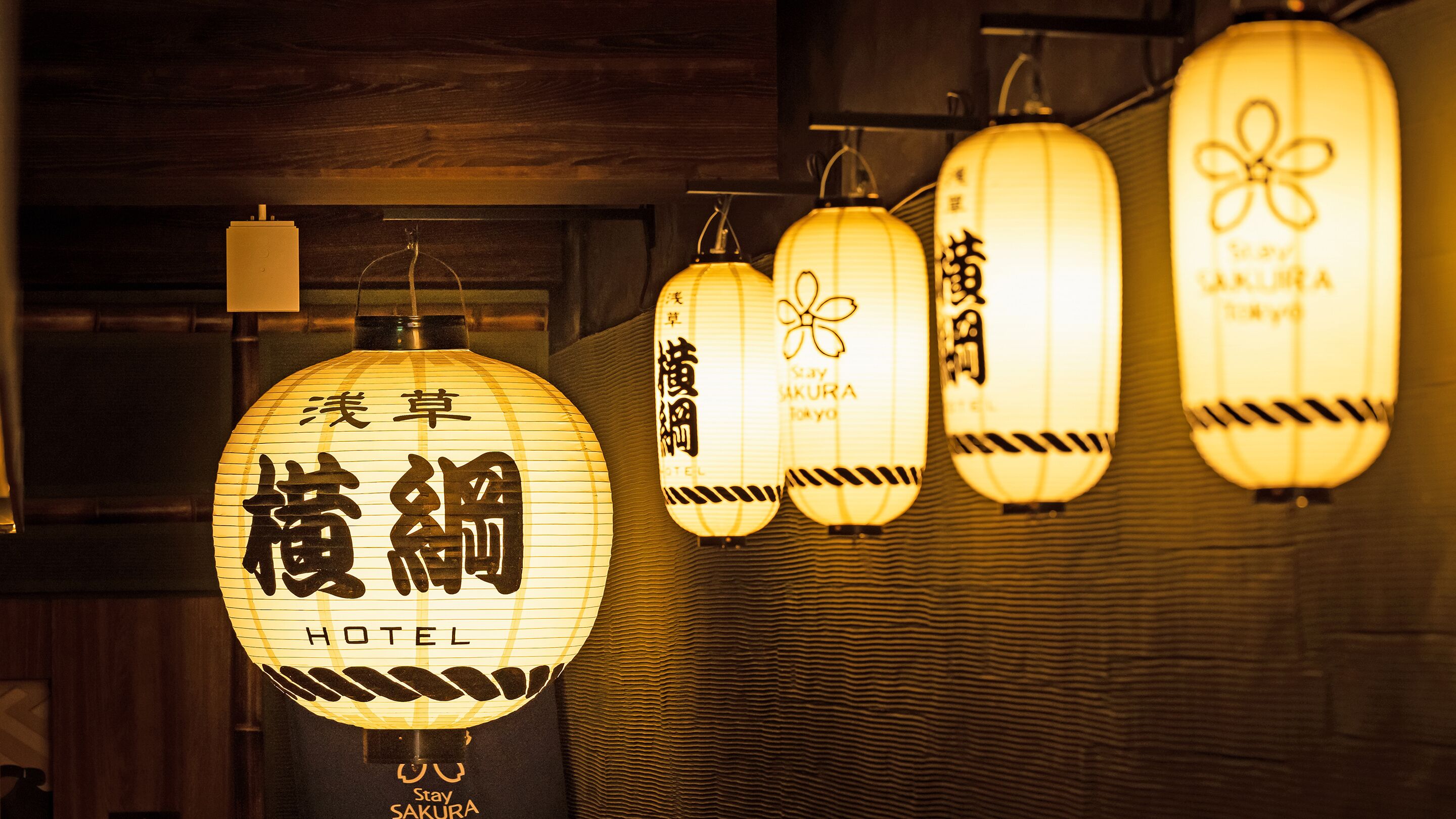 Una hilera de faroles japoneses tradicionales con el texto "Stay Sakura Hotel" y "Hotel" visible.