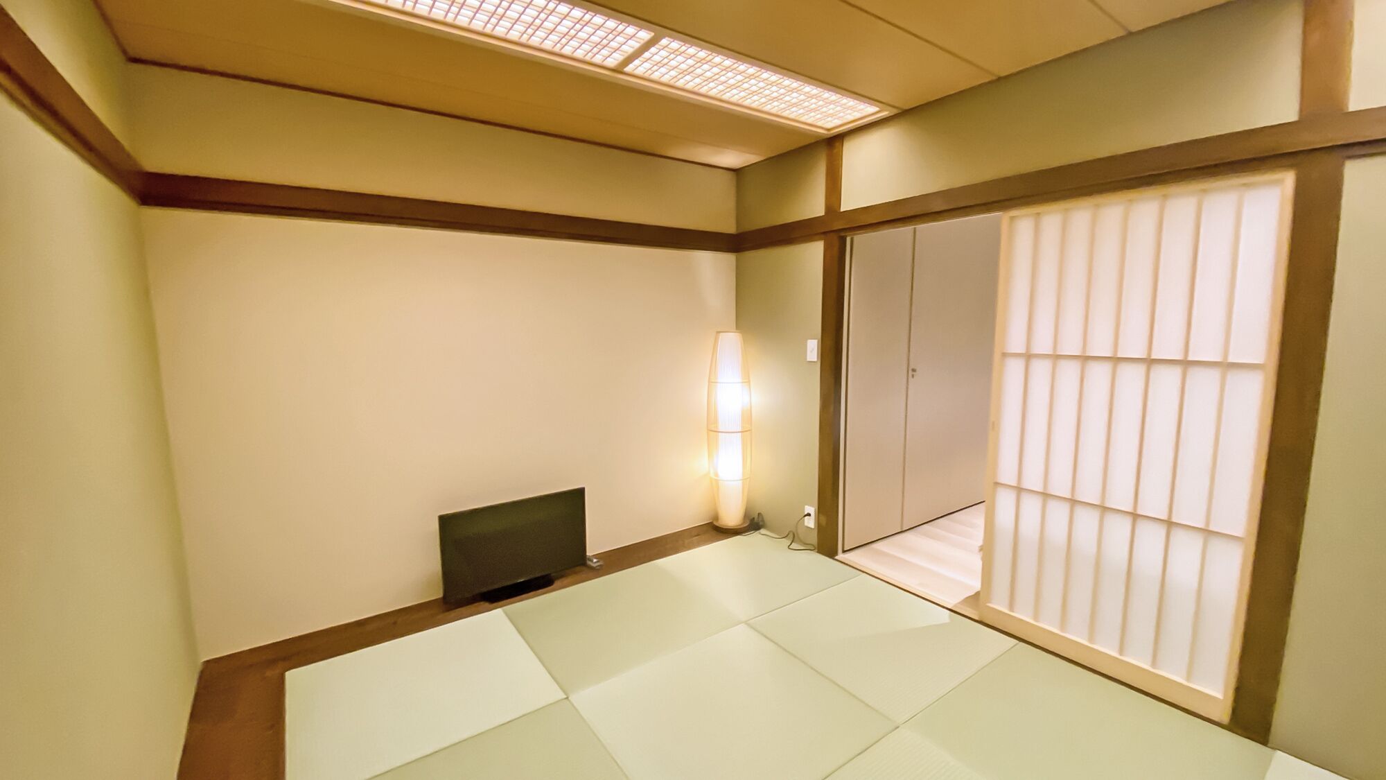 Una habitación tradicional japonesa con suelo de tatami, puertas correderas y una pequeña mesa.