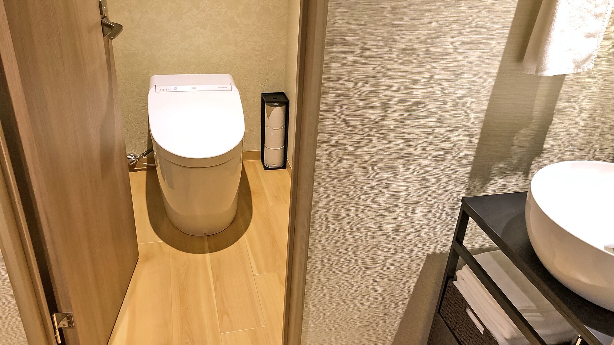 Un baño pequeño con inodoro, bidé y lavabo sobre una encimera oscura.