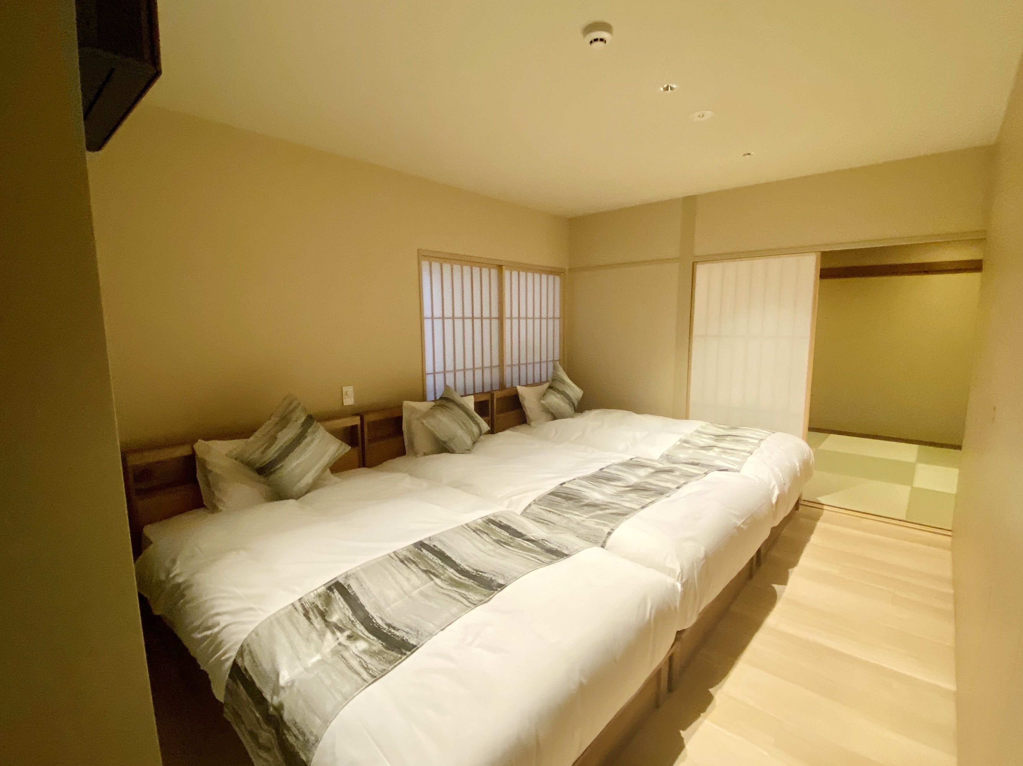 Ein Hotelzimmer mit einem großen Bett, einem Fenster mit Jalousien und einem Schachbrettfußboden.