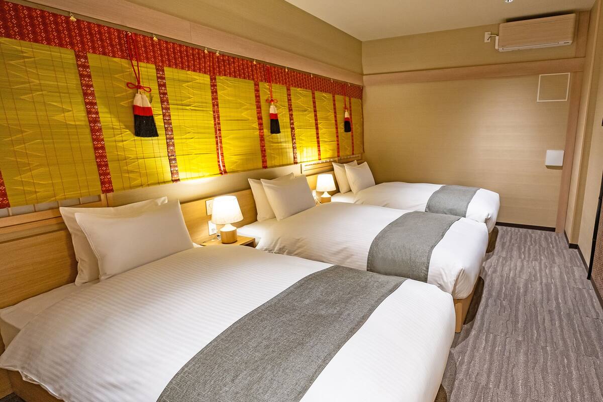 A hotel room with two beds, a TV, and a decorative headboard.