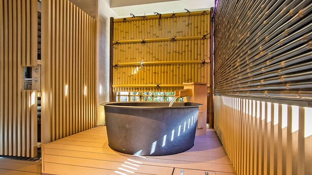 Un área de spa con un jacuzzi grande, listones de madera en las paredes y techo de bambú.