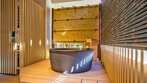 Un área de spa con un jacuzzi grande, listones de madera en las paredes y techo de bambú.