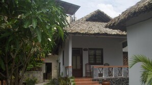A house with a thatched roof, a stone pathway, and potted plants. - Suoi Tien Mui Ne Resort (Mui Ne)