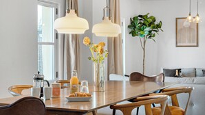 A dining area with a wooden table, chairs, a vase with flowers, a coffee pot, and a bottle of orange juice. - Haven - Popular 2-bdr Apt in Central Copenhagen (Copenhagen)