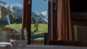 Vista desde una ventana con marco de madera, una mesa de vidrio y una copa de vino.