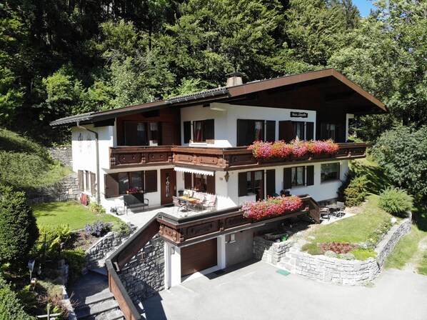 Un chalet à deux étages doté d’un balcon, d’un escalier en pierre et d’un jardin.