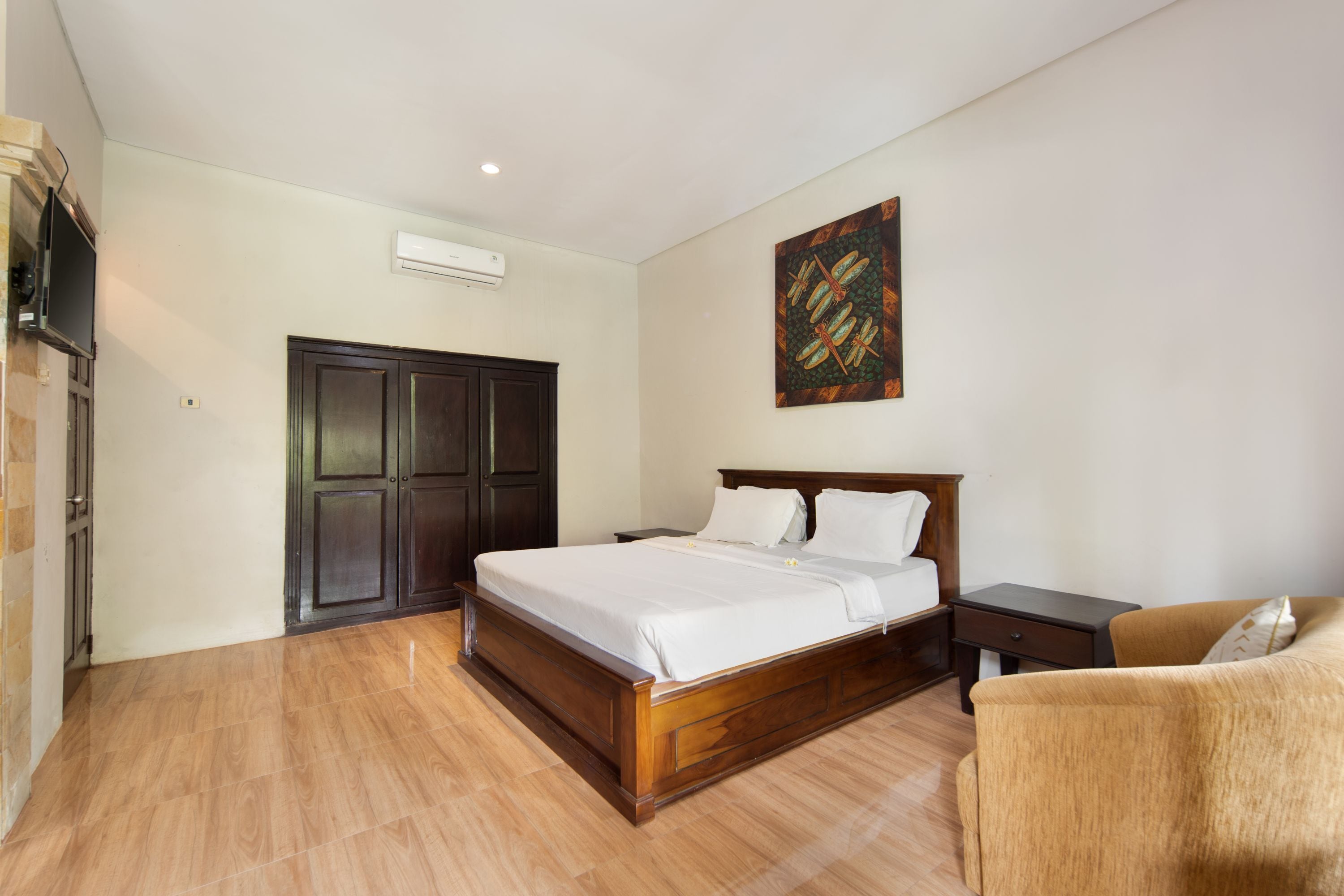 A bedroom with a wooden bed, a nightstand, a chair, a wardrobe, and a painting on the wall.