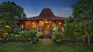A traditional house with a tiled roof, a central entrance with steps, and potted plants on either side. - Mahe Garden Inn and Villas (Kuta)