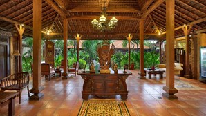 A spacious lobby with a wooden ceiling, a central ornate table, and a large decorative sculpture. - Mahe Garden Inn and Villas (Kuta)