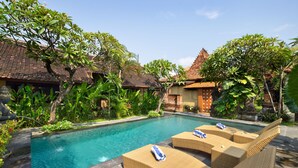 A swimming pool with lounge chairs and tropical plants. - Mahe Garden Inn and Villas (Kuta)