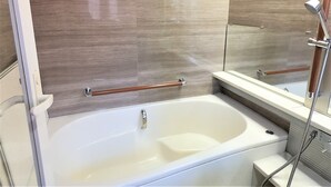 A modern bathroom with a bathtub, a shower area, and a mirror. - Koinami (Shima)