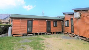 A small, single-story wooden cabin with a green roof, a front door, and a window. - Koinami (Shima)