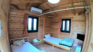 A wooden cabin room with two beds, a small table, an air conditioning unit, and two windows with curtains. - Koinami (Shima)