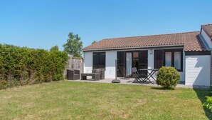 A single-story house with a tiled roof, a patio with outdoor furniture, and a small garden. - Enjoy with parking by Interhome (De Haan)