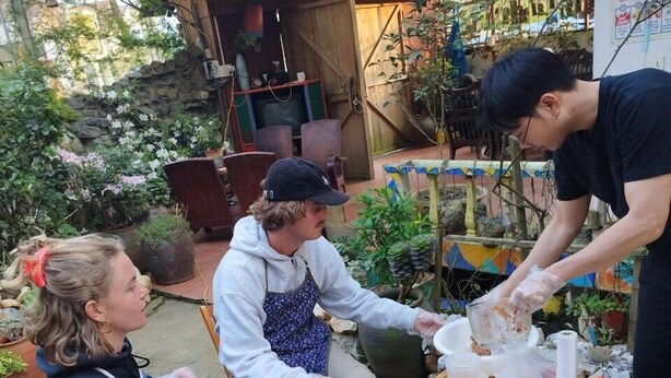 A group of people preparing food outdoors with a table full of ingredients and cooking utensils. - Saigonese Trekking House - Hostel (Sa Pa)