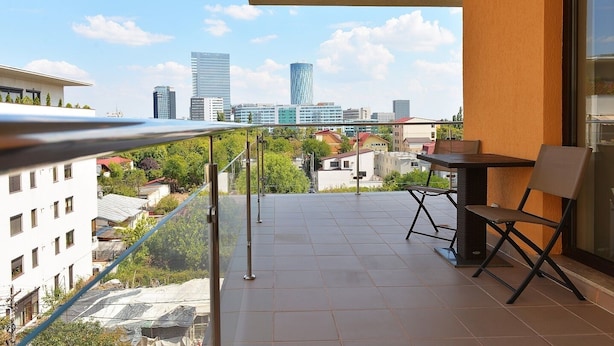 Ein Balkon mit Blick auf eine Stadtlandschaft, einem Tisch und zwei Stühlen.