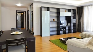 Ein modernes Wohnzimmer mit einer Couch, einem Couchtisch, einem Fernseher und einem Bücherregal.