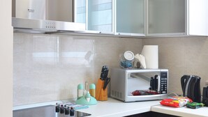 Eine moderne Küche mit Edelstahlgeräten, dunklen Schränken und einer Mikrowelle auf der Arbeitsfläche.