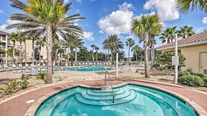 A swimming pool with a 2 ft 2 in depth, surrounded by palm trees and lounge chairs, with a clear sky above. - Resort-Style Perks! Riverfront Gem in Palm Coast (Palm Coast)