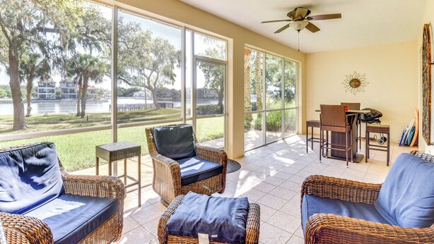 A spacious room with wicker furniture, large windows, and a ceiling fan. - Resort-Style Perks! Riverfront Gem in Palm Coast (Palm Coast)