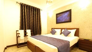A hotel room with a bed, a nightstand, a wall-mounted TV, and a curtain. - Sky 14 Hotel Apartments (Malabe)