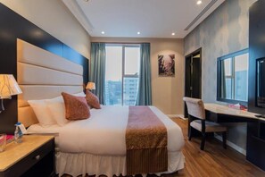 A hotel room with a large bed, a desk, and a chair. - Hyatt Buyutat Service Apartments (Riyadh)