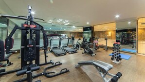 Un gimnasio moderno con diversos equipos de ejercicio, incluyendo cintas de correr, máquinas de pesas y pesas libres.