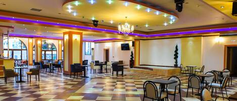 A spacious lobby with a checkered floor, multiple seating areas, and a chandelier.