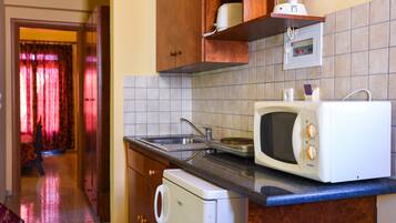 A kitchen with a microwave, sink, and a dishwasher. There is a wooden cabinet above the microwave and a tiled backsplash.