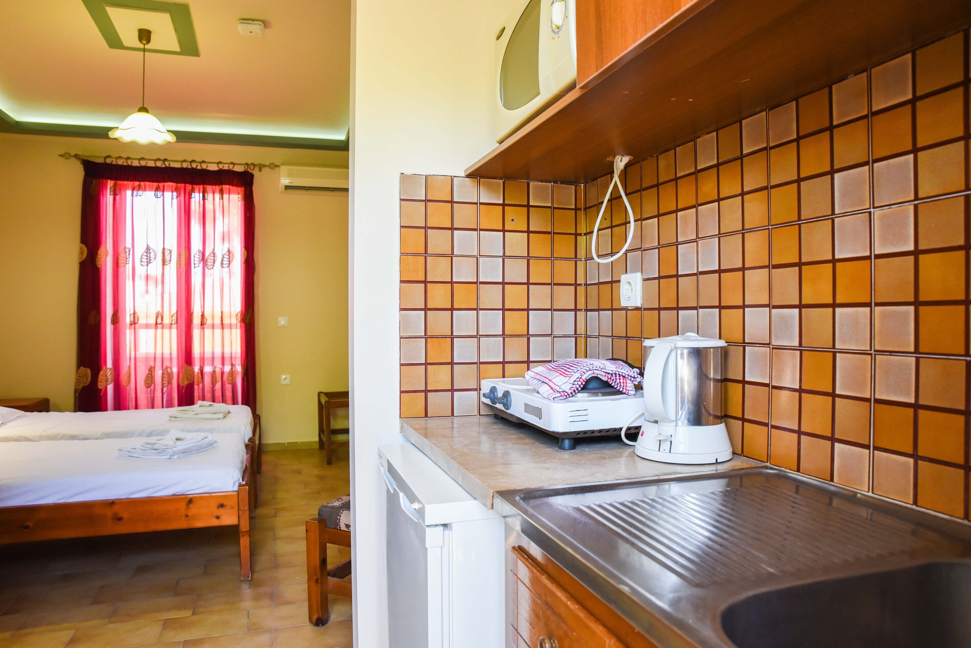 A room with a bed, a kitchenette with a microwave, and a tiled backsplash.