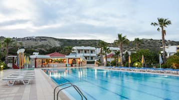 Relax by the resort pool surrounded by lounge chairs and umbrellas, with a stunning view of the surrounding landscape.