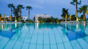 A swimming pool with a view of a building and palm trees in the background.