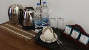 A hotel room with a wooden table, a kettle, two bottles of water, a cup, salt and pepper shakers, and a tray with a menu. - Hotel Akashayaam (Negombo)