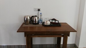 A small wooden table with a kettle, a water bottle, glasses, and a tray with cups and a box of tissues. - Hotel Akashayaam (Negombo)