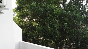 A small balcony with a table and two chairs, a patterned tablecloth, and a view of dense green foliage. - Hotel Akashayaam (Negombo)