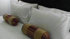 A neatly made bed with white linens and two decorative pillows. - Hotel Akashayaam (Negombo)