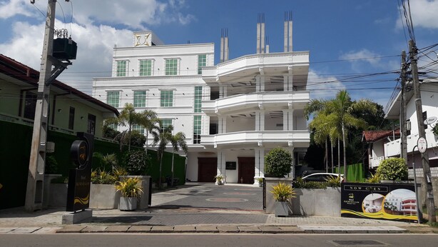 A multi-story hotel with a white facade, green window frames, and a central entrance. - Hotel Akashayaam (Negombo)