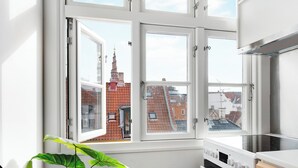 A kitchen with a large window, a stove, and a plant. - Saint - Nice 1-bdr Apt by the Canals (Copenhagen)