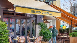 An outdoor cafe named Bistro Central with wicker chairs and tables, a large planter, and a yellow awning. - Saint - Nice 1-bdr Apt by the Canals (Copenhagen)