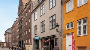 A street with buildings, a café with outdoor seating, and a red flag. - Saint - Nice 1-bdr Apt by the Canals (Copenhagen)
