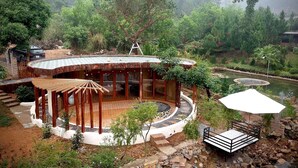 A circular wooden structure with a covered seating area, surrounded by a garden and a pond. - U Lesa Retreat Nha Ben Rung (Hanoi)