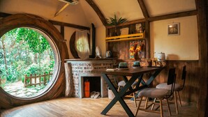 A cozy room with a large round window, a brick fireplace, wooden furniture, and a small plant on a shelf. - U Lesa Retreat Nha Ben Rung (Hanoi)