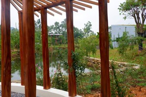 A wooden pergola structure with a view of a pond and surrounding greenery. - U Lesa Retreat Nha Ben Rung (Hanoi)